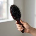 Woman holding 7th Heaven hair extensions brush designed for gentle detangling and extension care