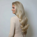 Angled view of 20 inch Rooted Creamy Beach Blonde clip-in hair extensions styled in loose flowing waves